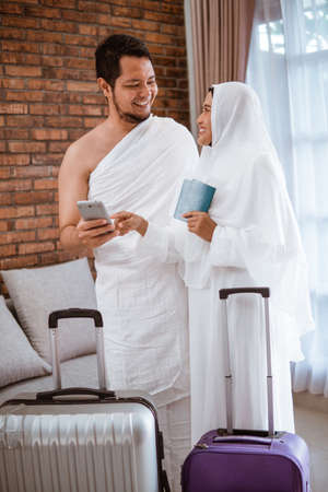 portrait of muslim couple making a phone call while umrah and hajiの写真素材