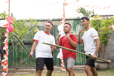 three young Asian men in red and white attributes and hold spiky bamboo at Indonesia's Independence...