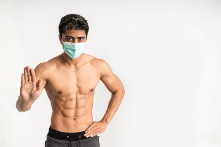 asian muscular man wearing a mask with a refuse hand gesture and one hand on the waist stand facing...