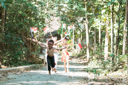 having fun group of kids running without clothes when holding small the red and white flag and raised the flagの写真素材