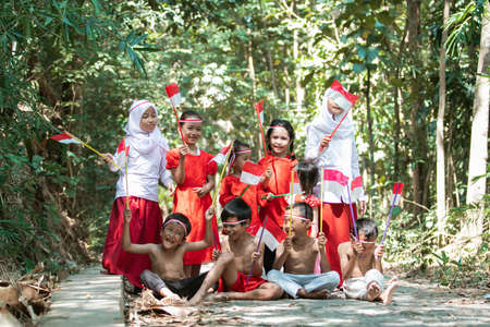 having fun group of asian kids holding the red and white flag and raised togetherの写真素材