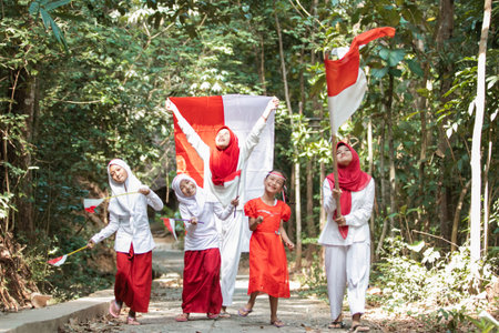 group of asian little girls walk with laugh and sing a song when holding and raise the red and white...