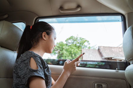 Teenage girl smile when holding a smartphone while sitting in the car