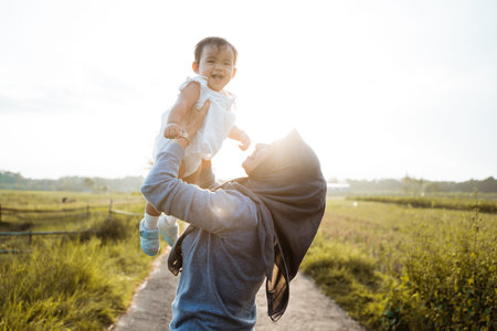 Asian mother raising her daughter when standing the road in the middle of the rice fields