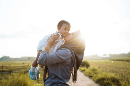 a mother kissing when raising her daughter when standing the roadの写真素材