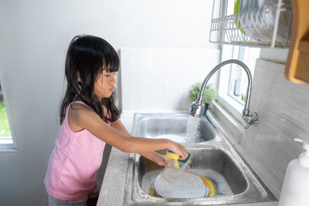 asian little girl wash the dishes