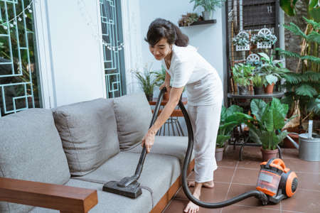 Beautiful young woman cleaning with vacuum cleanerの写真素材