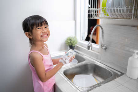 kid washing the dishes and lookingの写真素材