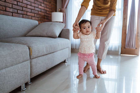 mother help her baby to walk her first stepの写真素材