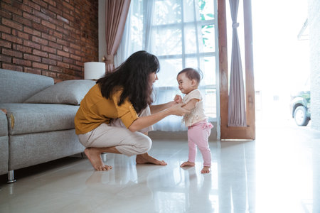 mother help her baby to walk her first step