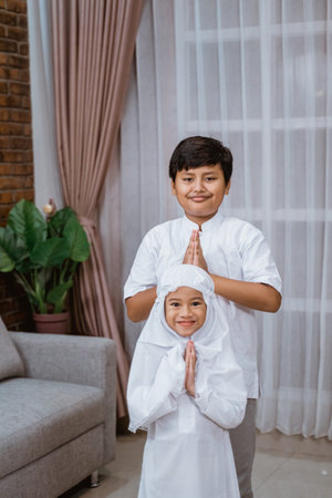 Asian boy brothers wearing a Koko shirt and sisters wearing veil say Salaamの写真素材