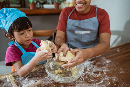 Happy Asian father and daughter having happy time while cooking togetherの写真素材
