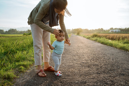 mother help her baby to walk her first step