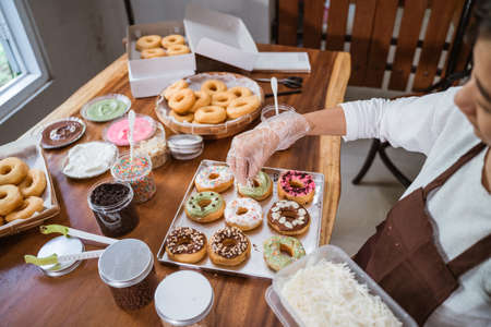 Chef sprinkles donuts with grated cheese to decorate the donuts on the tableの写真素材