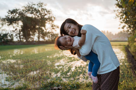 a portrait of a happy mother hugging her child in the rice fieldsの写真素材