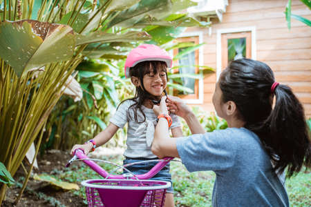 portrait of a mother helping her daughter wear a helmetの写真素材