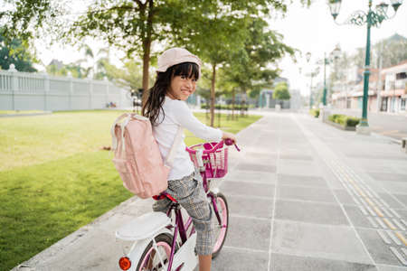 girl riding a bicycle in the park going to school by herselfの写真素材