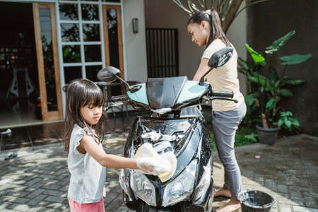 potrait happy young girl and little girl washing motorcycleの写真素材