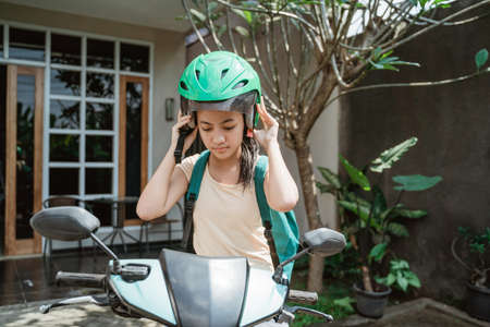 teenage girl close up while wearing and fasten her motorcycle helmetの写真素材