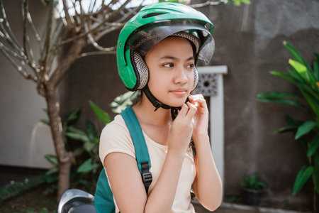 teenage girl close up while wearing and fasten her motorcycle helmet