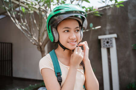 teenage girl close up while wearing and fasten her motorcycle helmetの写真素材