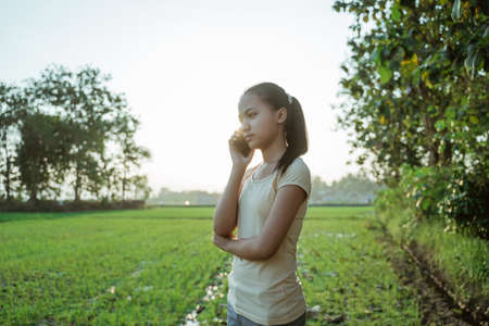 portrait of a beautiful young girl looking while holding a cellphoneの写真素材