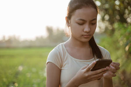 portrait of a sad young girl looking while holding a cellphoneの写真素材