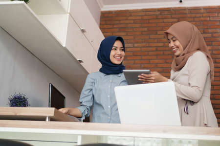 portrait of beautiful muslim women explaining project on tablet to her partnerの写真素材