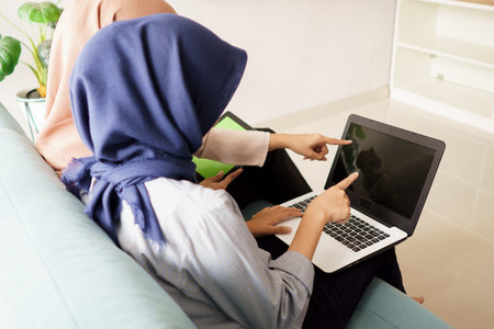 portrait of beautiful muslim women explaining project on laptop to her partner