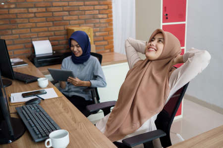 portrait of a beautiful muslim woman who is very happy to work with her partner holding a tabletの写真素材