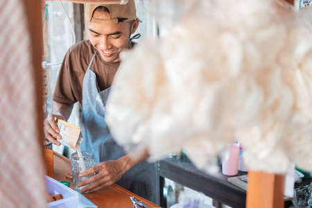 man seller the cart stall in apron makes drinks for customerの写真素材