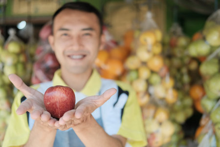 The shop assistant hands over the apples with two hands