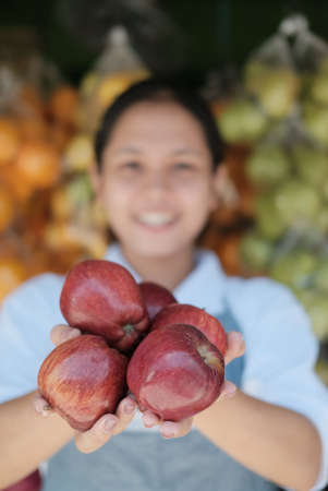 Fresh red apples in the hands of a fruit shop clerkの写真素材