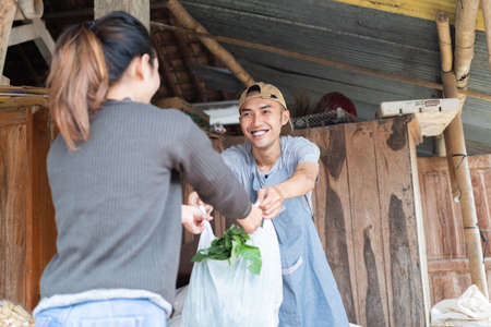 smiling men holding plastic bags given to female buyerの写真素材