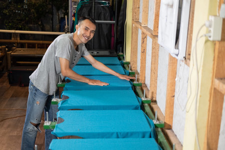male worker smile while preparing t-shirts that are placed on the board