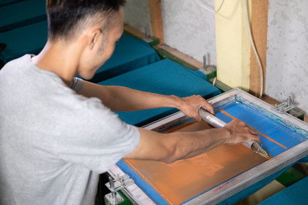 Young confident, experienced male working with squeegee on a small factory