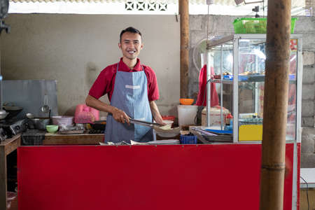 The stall waiter stands holding tongs while preparing the side dishesの写真素材