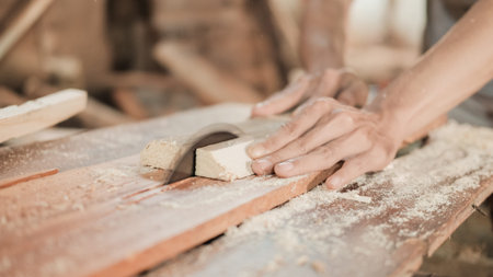 close up of a carpenters hand cutting wood planks using a circle saw