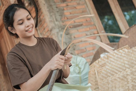 Asian women smile using a knife to make bamboo slats to make woven bambooの写真素材
