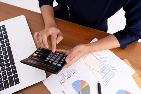 Close up business woman calculating her business profits and working on a laptop.