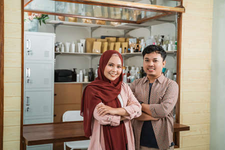 portrait young man and muslim woman selling packaged productsの写真素材