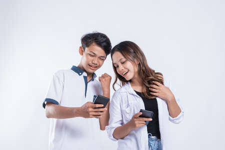 Portrait of happy university youth discussion looking at cell phonesの写真素材