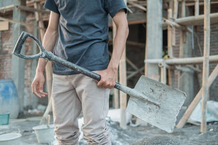 close up of a builders hand carrying a shovelの写真素材