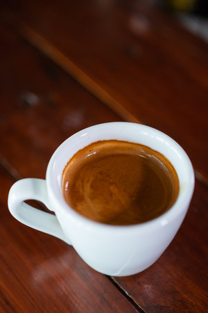 A cup of coffee in wooden background.