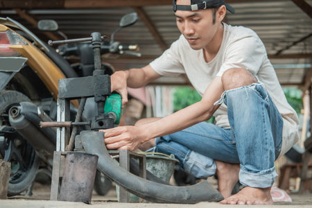 Tire repairman pours fuel into a traditional press when patching tires