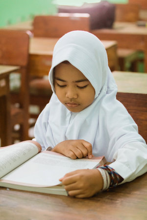 a portrait of an indonesian primary school student reading a textbookの写真素材