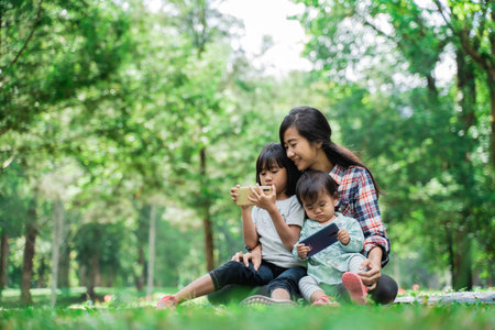 Portrait of a mother accompanying her child to play cellphonesの写真素材