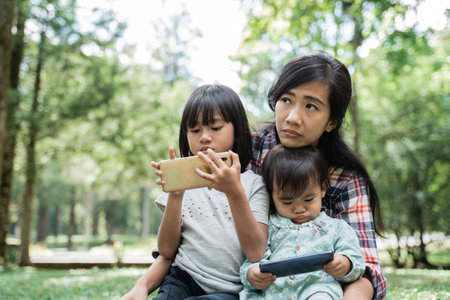 Portrait of a mother accompanying her child to play cellphonesの写真素材