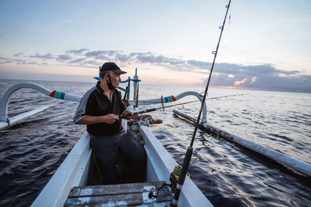 Portrait of a young fisherman fishing on a boatの写真素材