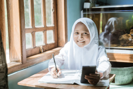 indonesian schoolgirl studying homework during her online lessonの写真素材